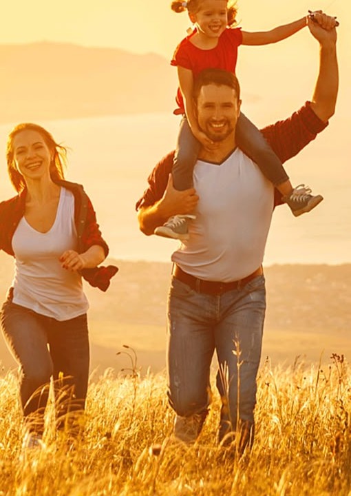 Familia feliz corriendo en un campo al atardecer