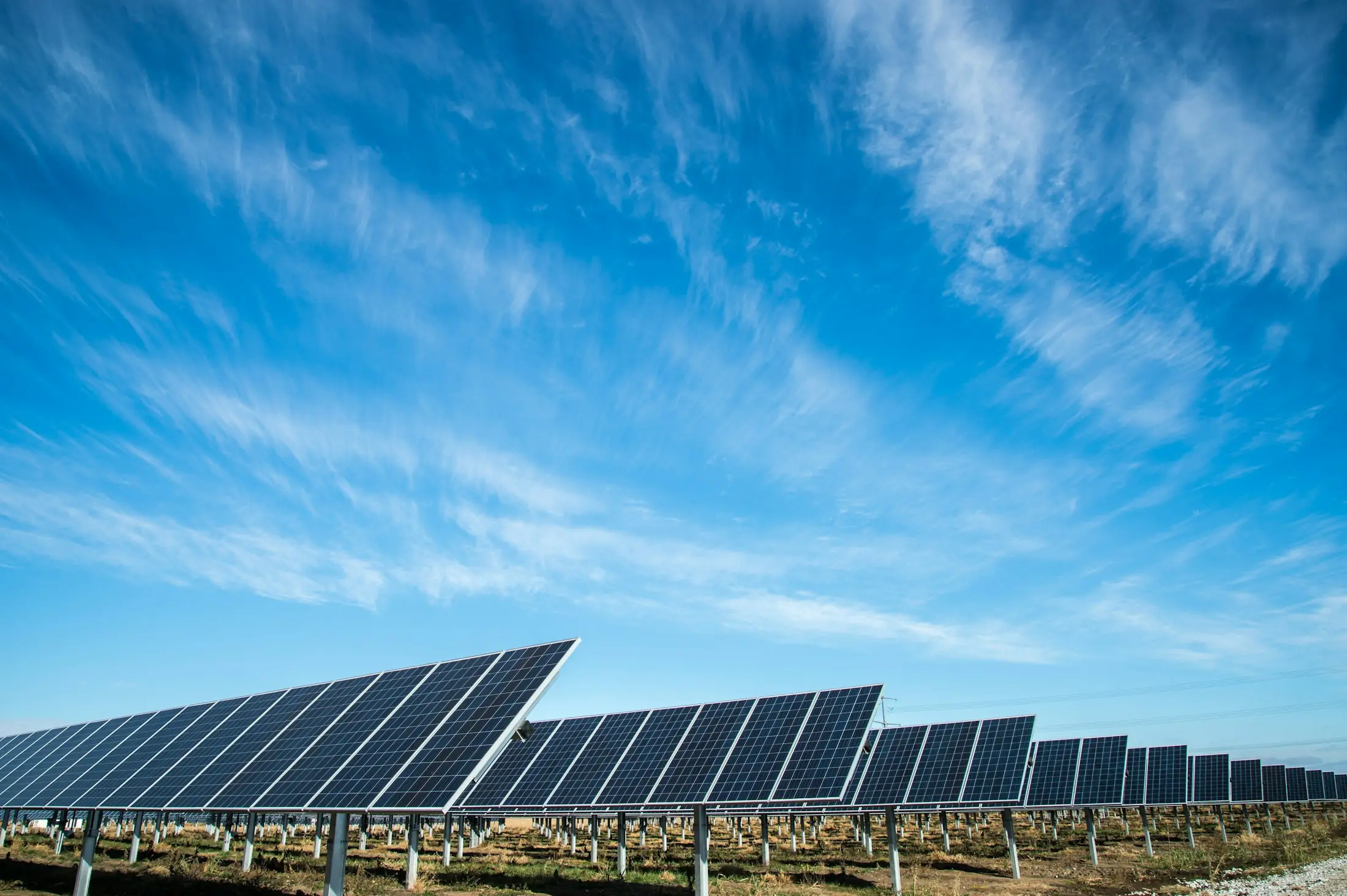 Hilera de paneles solares bajo un cielo azul con nubes finas